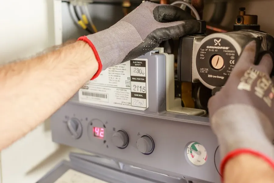 Plumber adjusting a boiler during a hot water upgrade for an Exeter bathroom