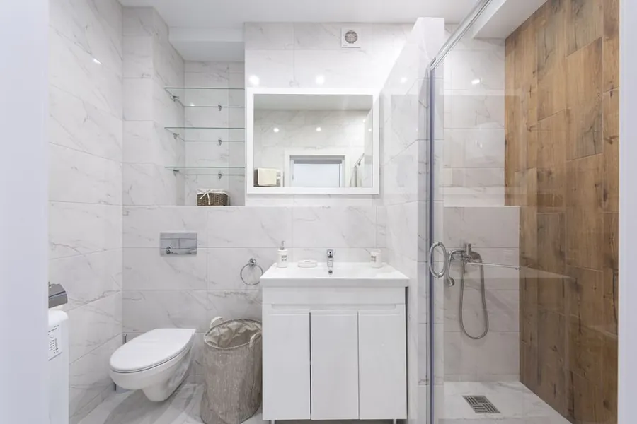 Marble-tiled Exeter bathroom with glass shower enclosure and wall-hung WC at a mid-level budget