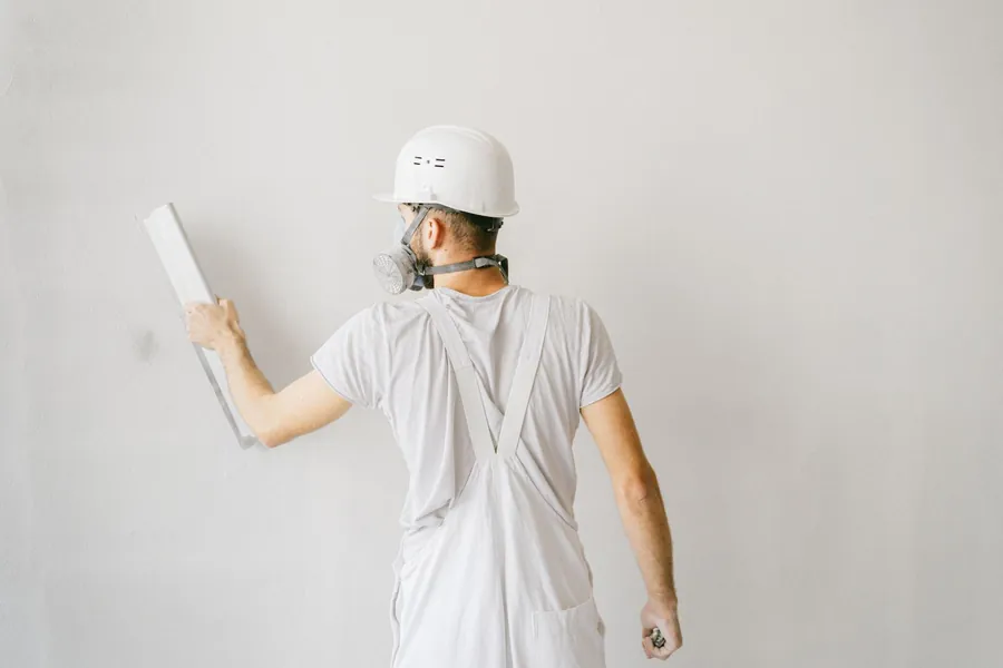 Plasterer skimming a wall during an Exeter bathroom fit, the making-good labour that takes the largest share of the budget