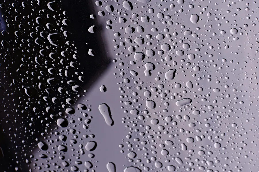 Close-up of hard water droplets drying on a shower glass panel in an East Devon bathroom