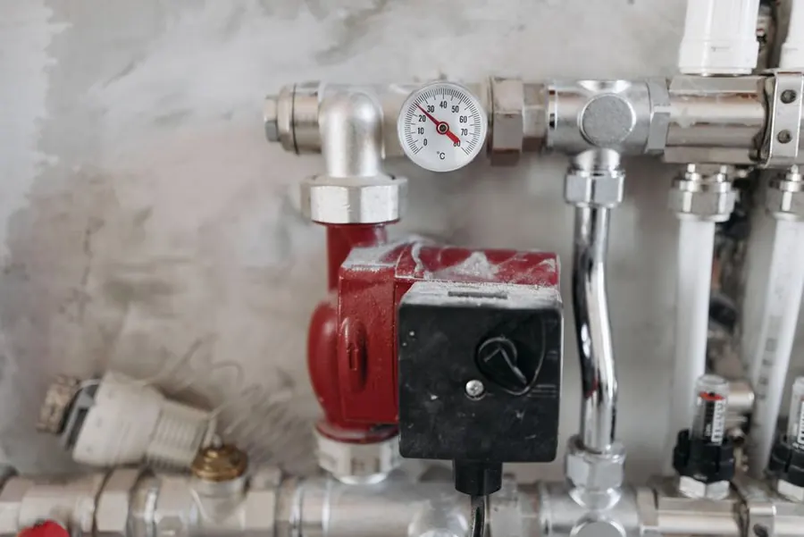 A pump and temperature gauge on domestic hot water pipework, where control of a holiday let's water temperature starts
