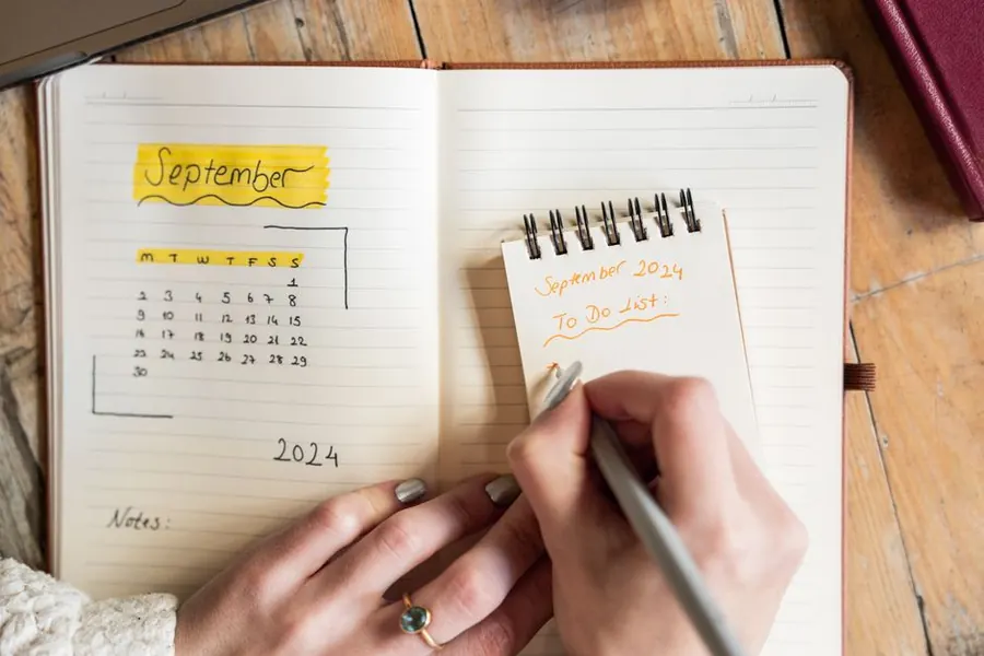 A hand-drawn calendar and to-do list in a notebook, planning a holiday let bathroom refit around the Devon season