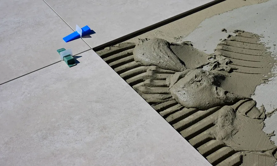 A ribbed adhesive bed and spacers under a large-format floor tile in an Exeter bathroom