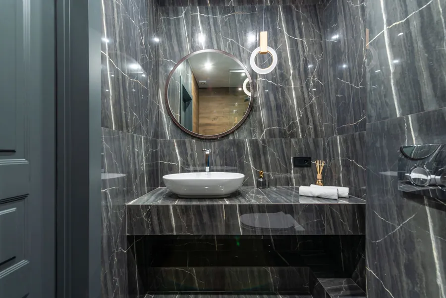 Polished dark marble walls in a bathroom, the reflective finish that shows every etch mark