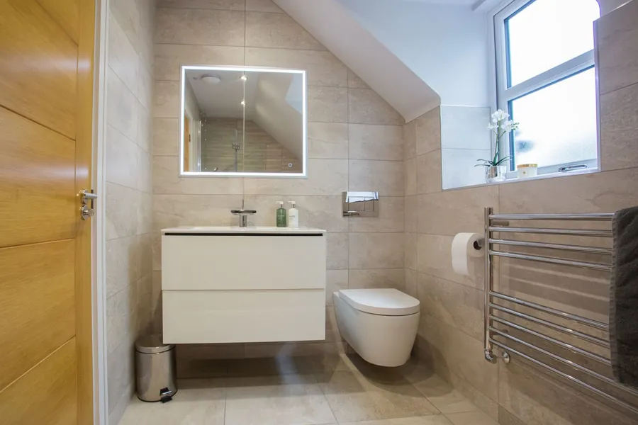 Top-floor bathroom with a sloping ceiling, wall-hung WC and vanity, the layout a converted Exeter loft room has to accept