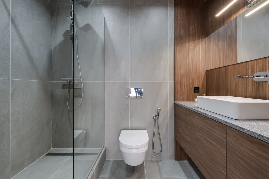 A walk-in shower with a single glass panel in a stone-tiled Exeter bathroom