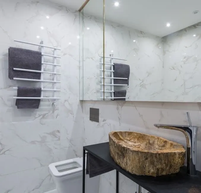 Marble bathroom wall with a carved stone basin on a slim black frame
