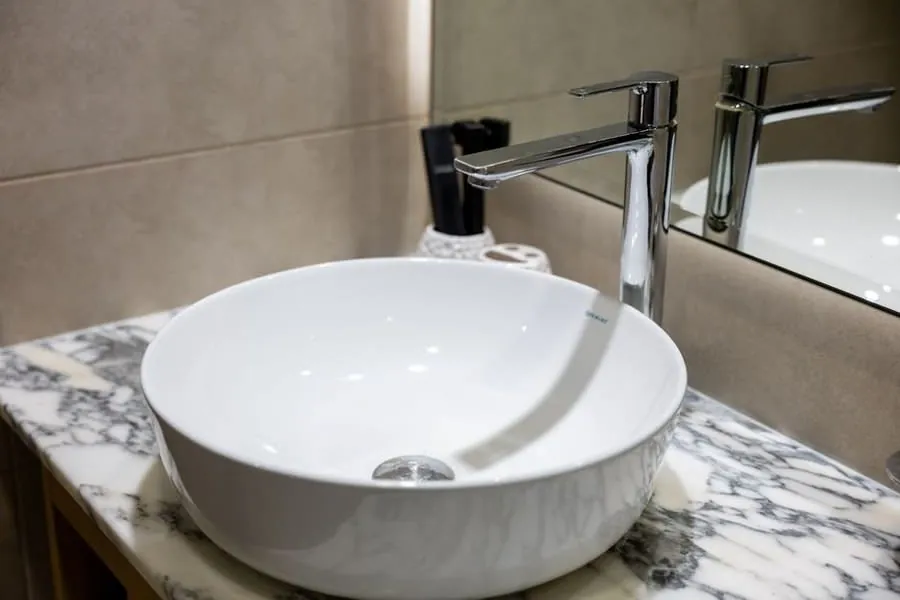 Counter-top basin and chrome mixer tap on a veined marble surface in an Exeter bathroom