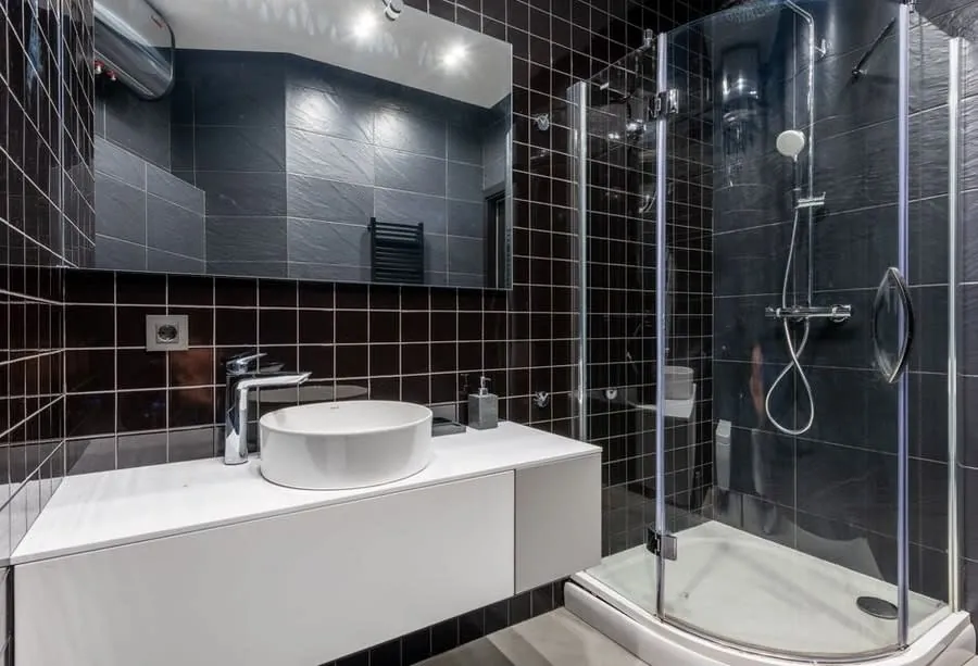Dark tiled bathroom with a white floating vanity and quadrant shower enclosure