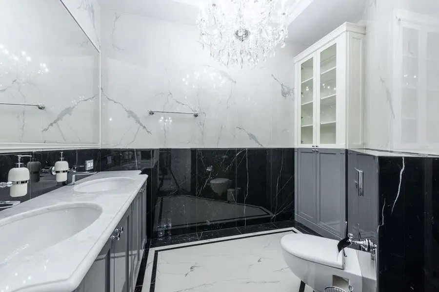 Renovated bathroom in Exeter with marble tiling, panelled units and a glass chandelier