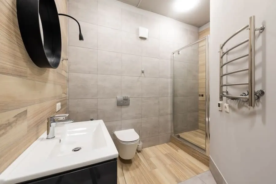 A wall-mounted extractor beside a window in a tiled bathroom