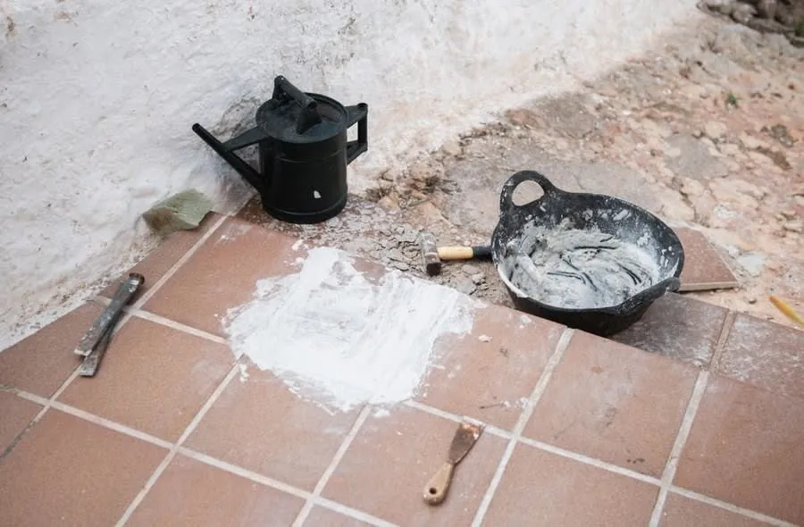 Tiled floor with fresh plaster and hand tools during the preparation stage