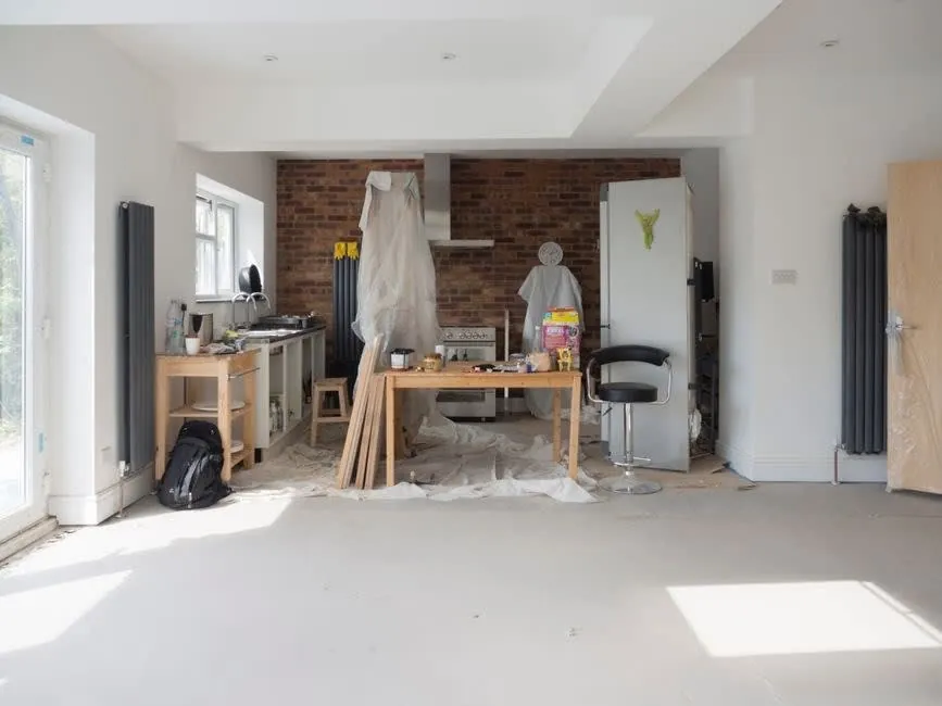 Interior mid-renovation with dust sheeting, tools and bare floors