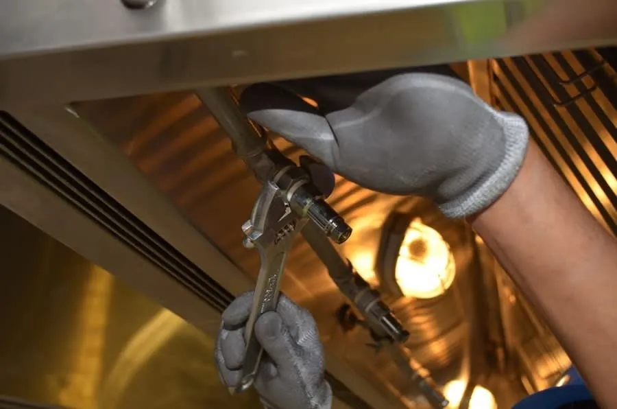 Gloved hands fitting a component during the second fix stage of a bathroom