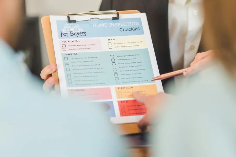 Checking a snagging list on a clipboard before releasing the final bathroom payment