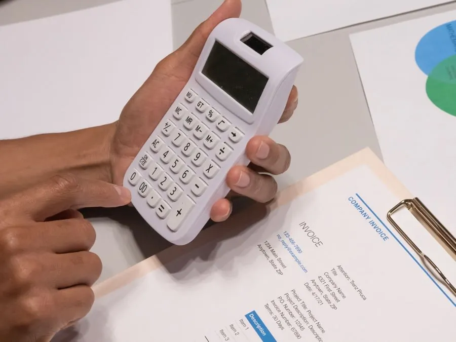 Working through a bathroom invoice with a calculator to check staged payment amounts