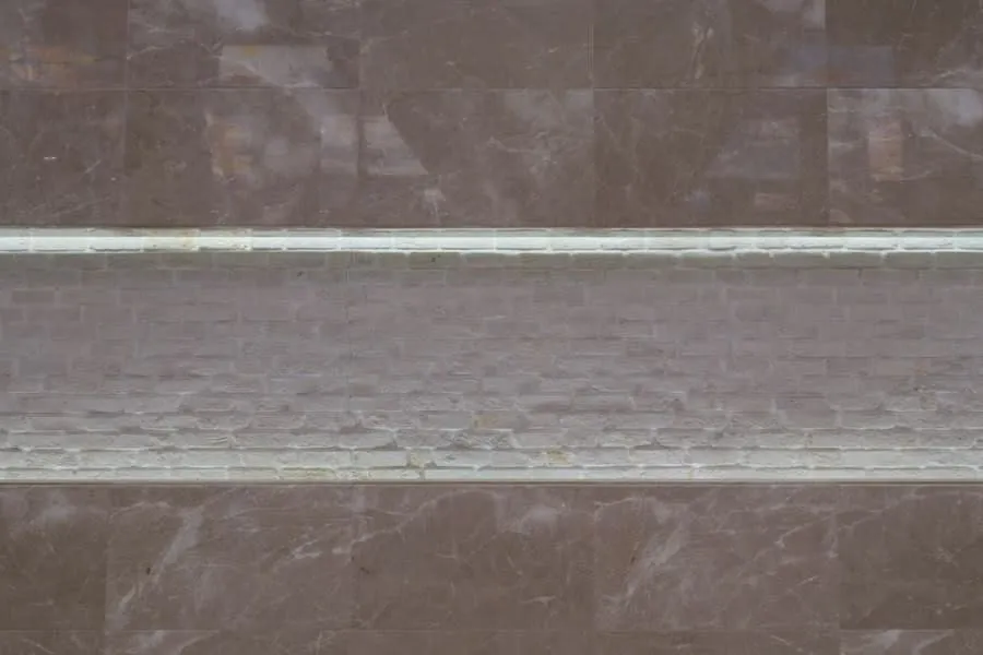 Grey marble wall tiling with a slim inset band running through the courses