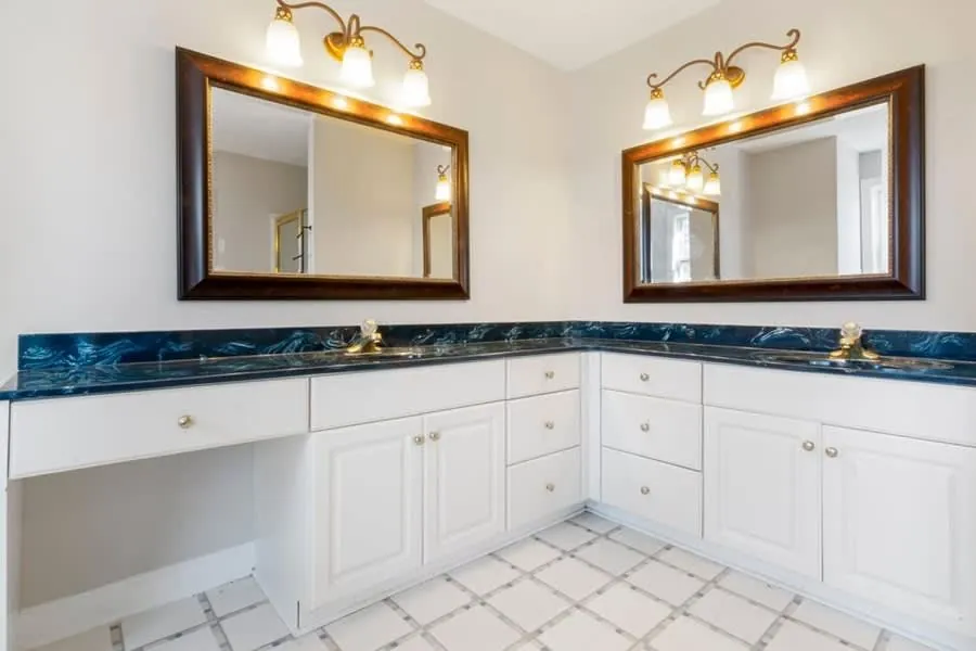 Twin mirrors flanked by wall lights over a bathroom vanity