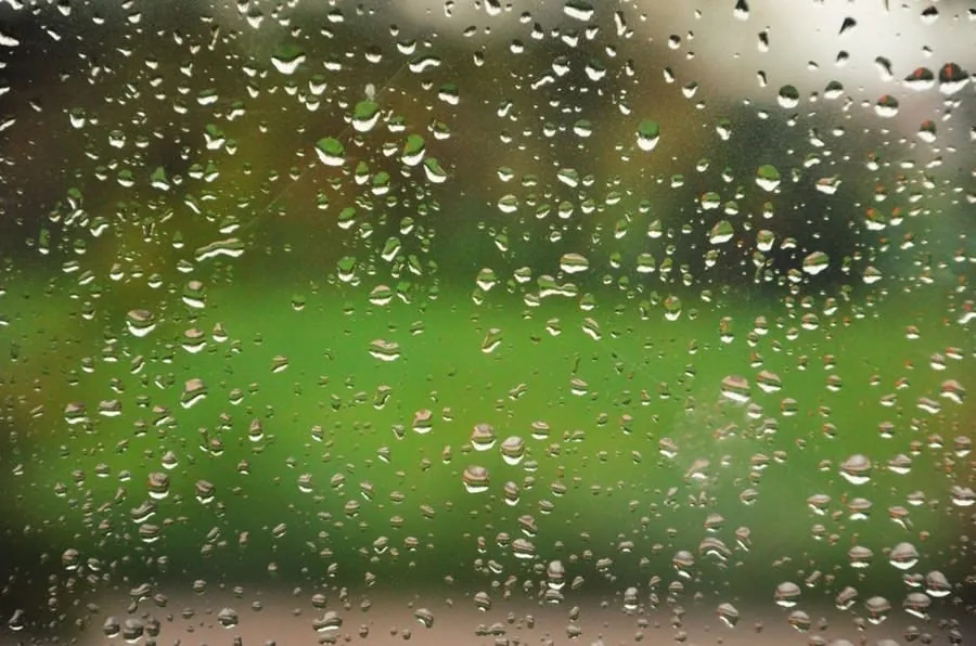 Water running down the inside of cold window glass as condensation forms
