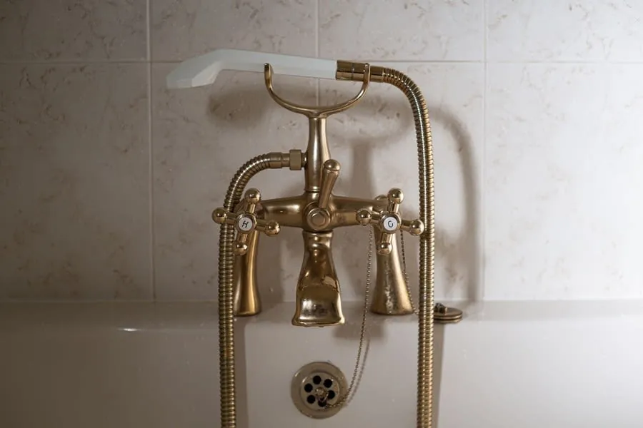 A traditional brass bath shower mixer with handset, a warm finish that hides limescale well