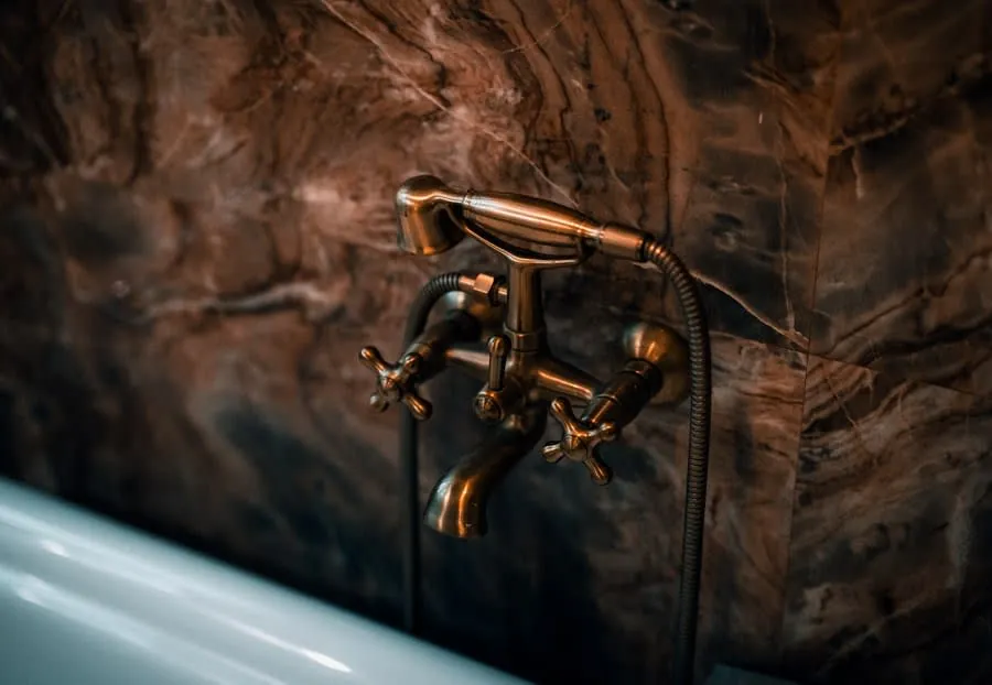 A brass tap against marble, showing the thin coated finish that sits over a solid brass body