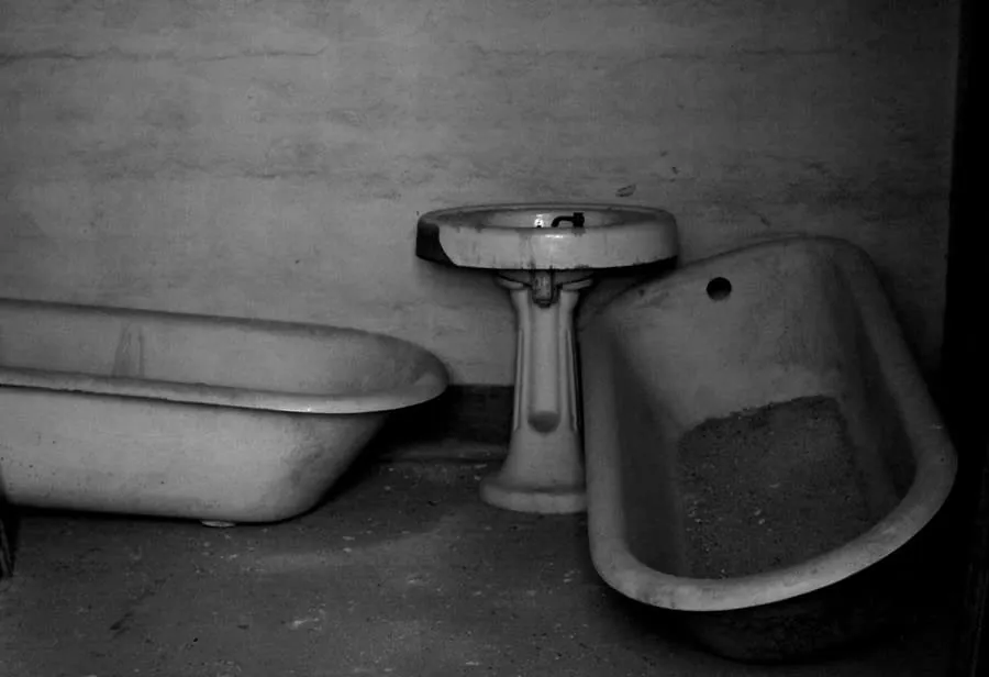 An old bathroom with a dated bath and basin, past the point of refurbishment