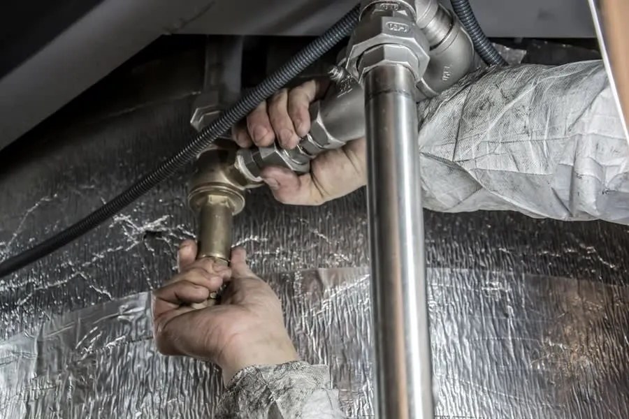 A plumber's hands fitting first-fix pipework against insulated walls