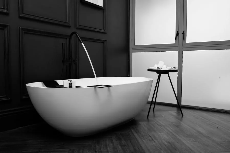 Freestanding bath filling from a floor-standing tap in a black and white bathroom