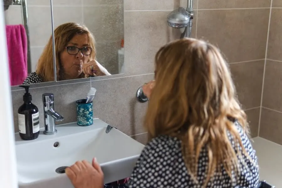 An older woman at a bathroom basin, the everyday use a future-proofed bathroom is designed around