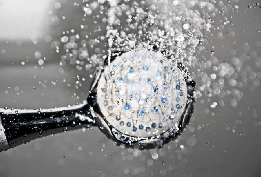 Water running from a shower head, where scale shortens component life in hard water areas