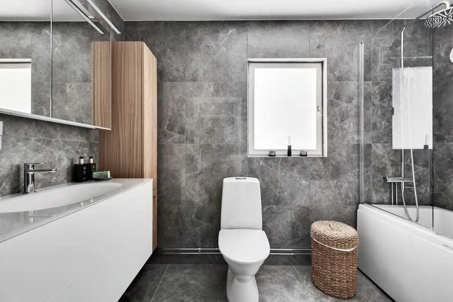 Neutrally specified grey tiled bathroom with a bath and separate shower