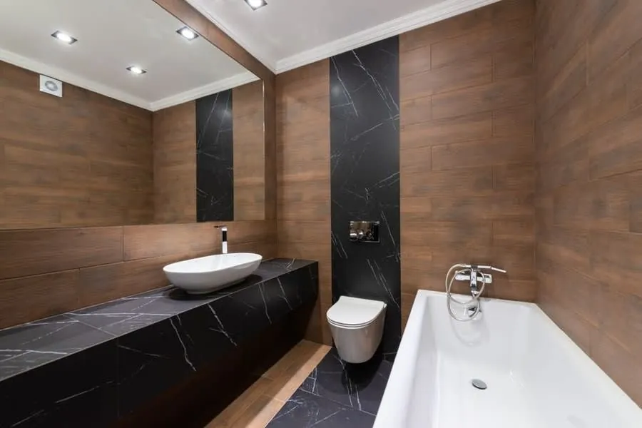 Compact bathroom in dark marble and wood with a wall-hung WC and counter-top basin