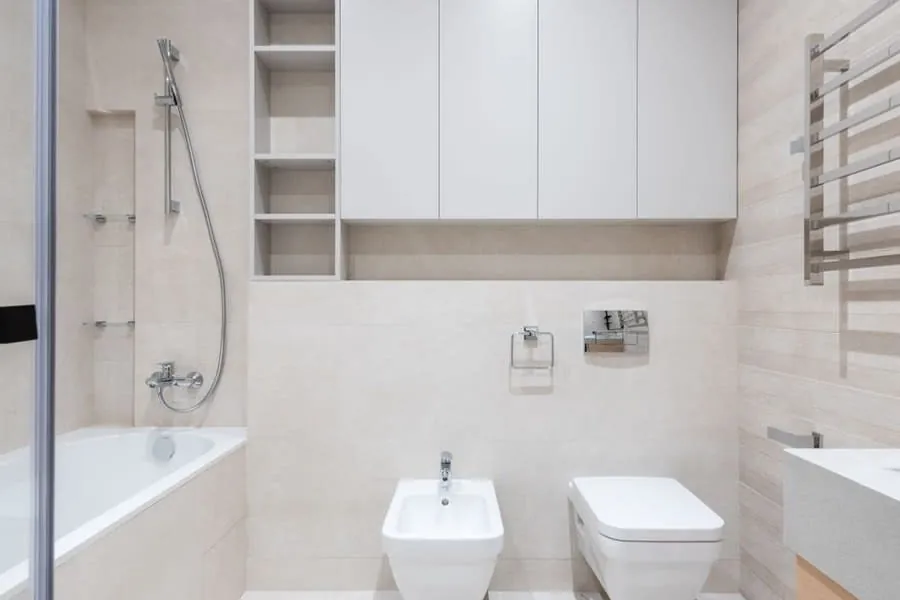 Narrow bathroom with a bath, wall-hung WC and recessed shelving making use of a tight footprint