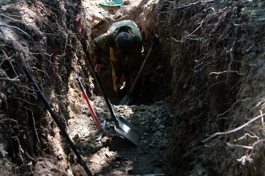A trench being dug by hand for a new drainage connection outside a house