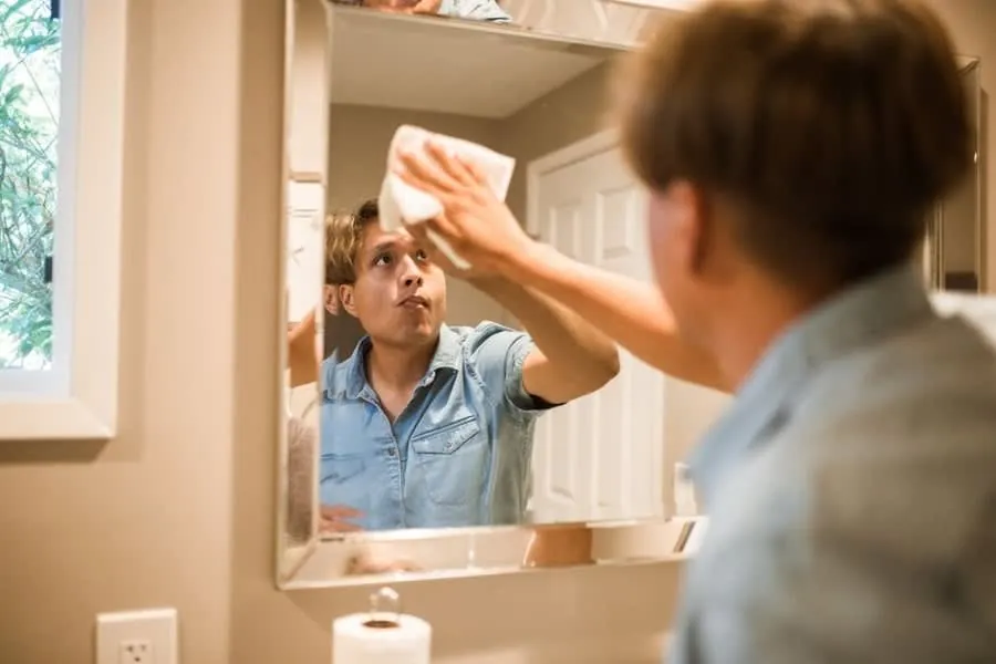 Wiping a hand across a mirror fogged with condensation after a shower