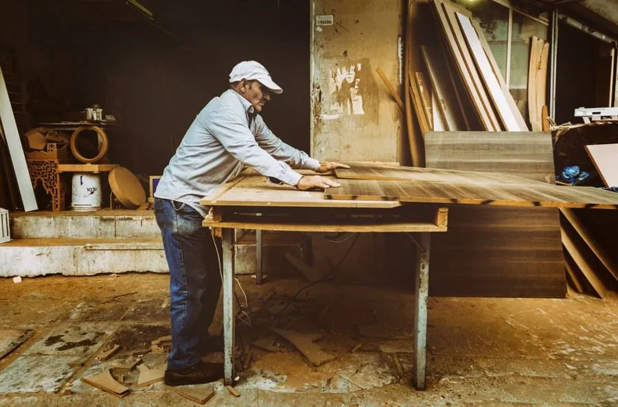 A joiner working a large sheet of walnut veneer in a workshop