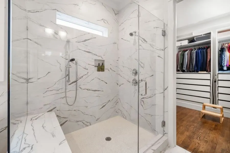 Walk-in marble shower with a built-in bench seat and level floor