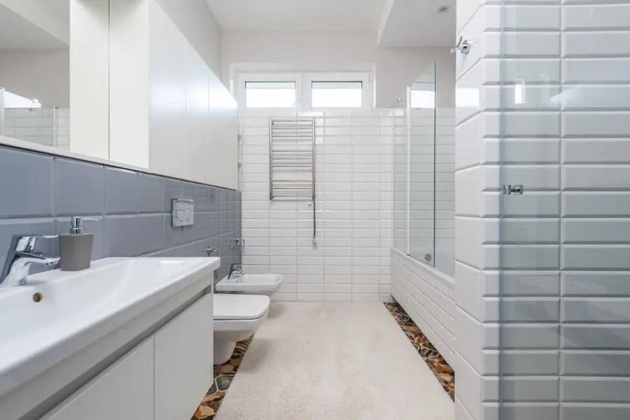 A wall-hung toilet and bidet in a white-tiled contemporary bathroom