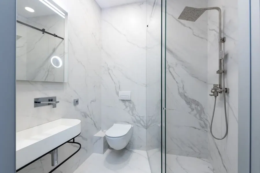 A marble bathroom with the WC set against one wall, the layout a drain run usually dictates