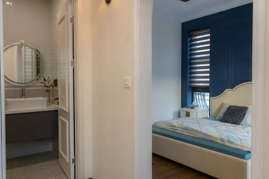 En-suite bathroom viewed through to a bedroom with panelled blue walls