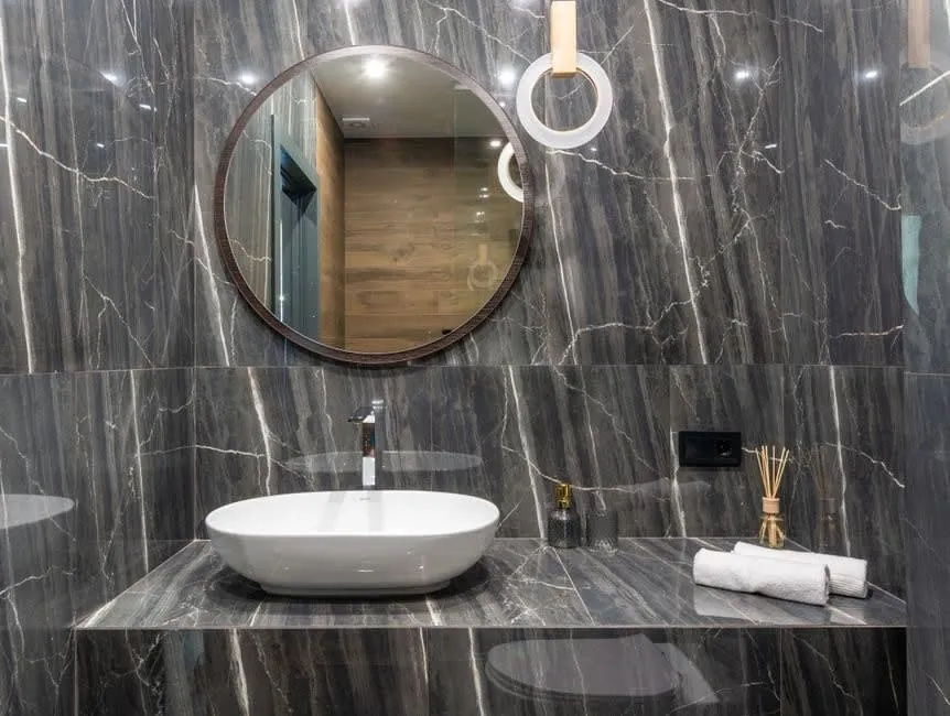 Grey marble bathroom in Exeter with a counter-top basin and round backlit mirror