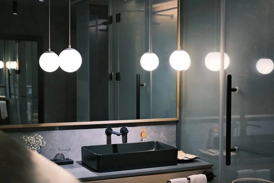 Brass tap detail on a dark stone vanity with pendant lighting above