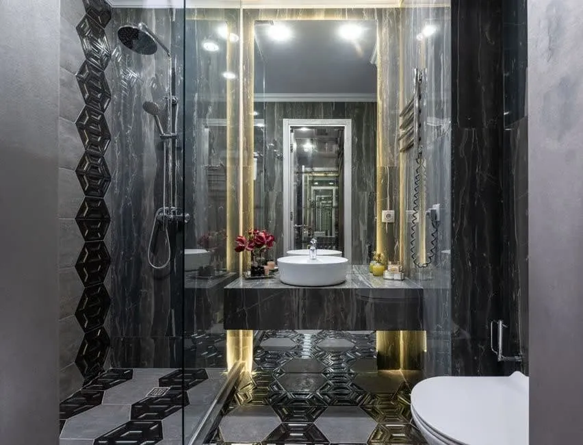 Dark marble bathroom with brass fittings and a mirrored recess