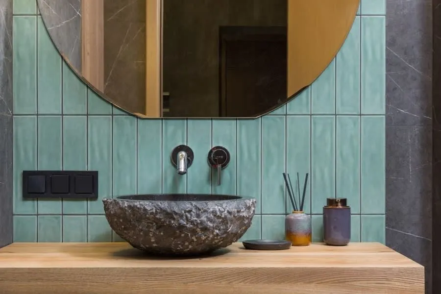 Hand-glazed green tiling with a carved stone vessel basin on a solid oak shelf