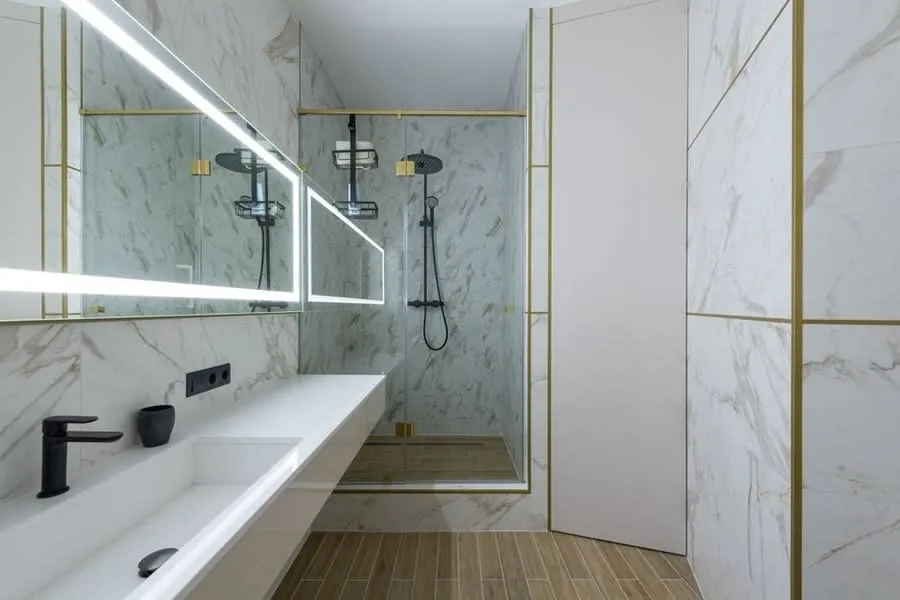 White marble walk-in shower with slim gold inlay detailing and a linear drain
