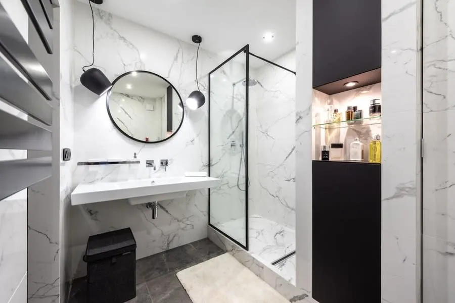 Luxury bathroom installation in Exeter with marble walls and a black-framed shower screen