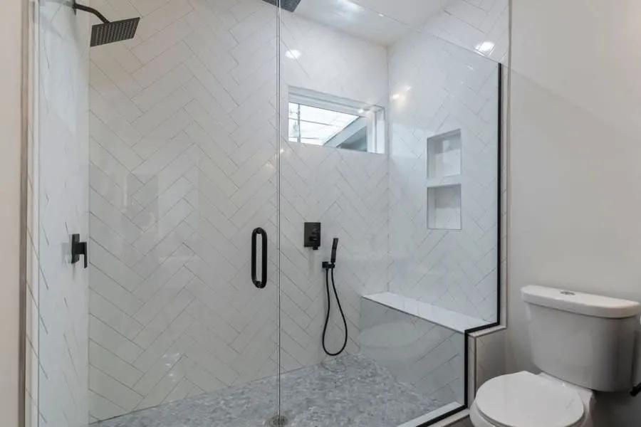 Walk-in shower in Exeter with herringbone wall tiling and a recessed shelf