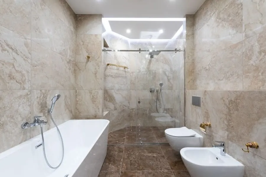 Travertine-tiled wet room in Exeter with a bath and separate shower area